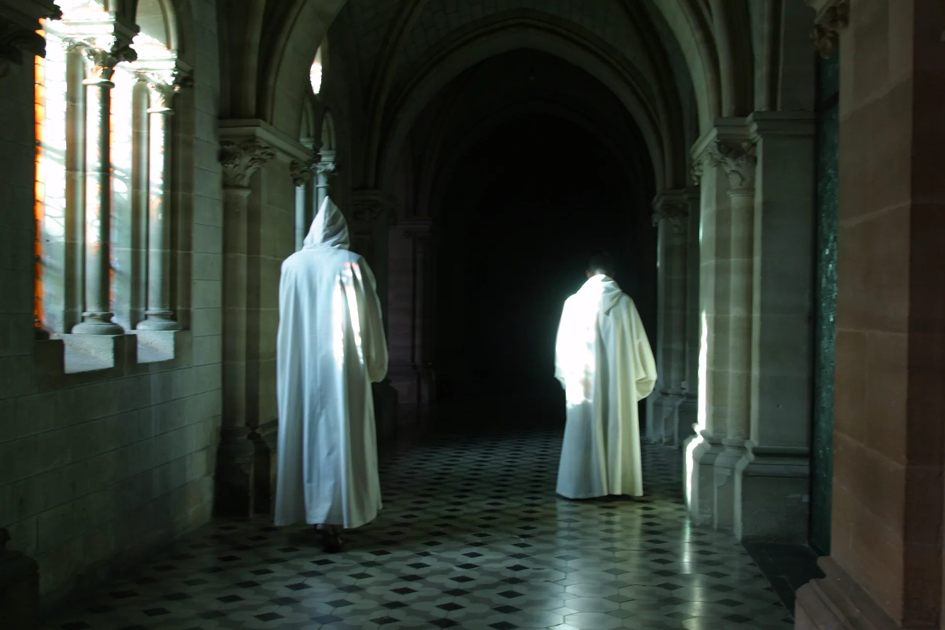 Deux moines en coules blanches dans la lumière du cloître