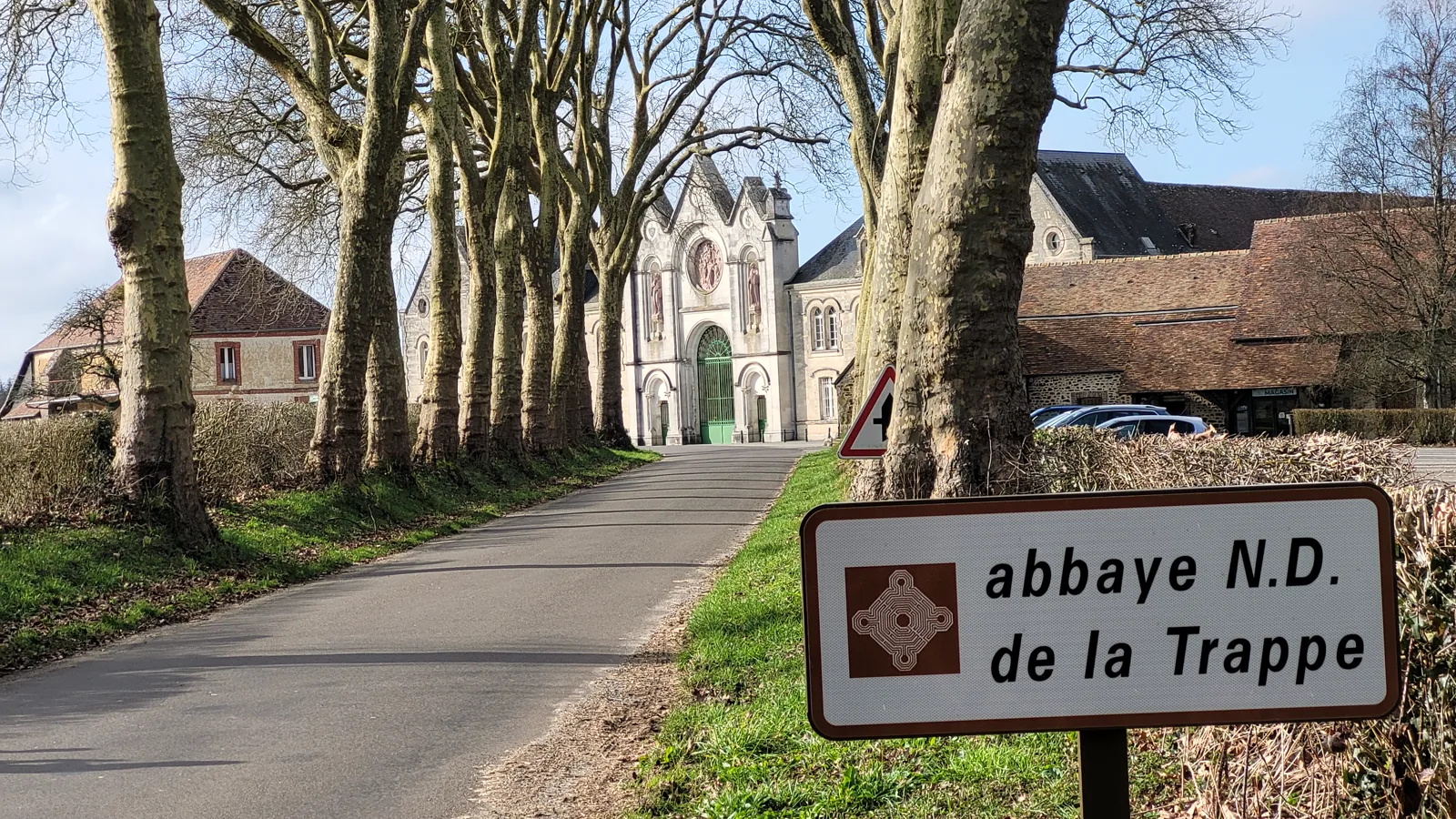 La route d’arrivée à l’abbaye, bordée de platanes, avec le panneau « abbaye N.D. de la Trappe »